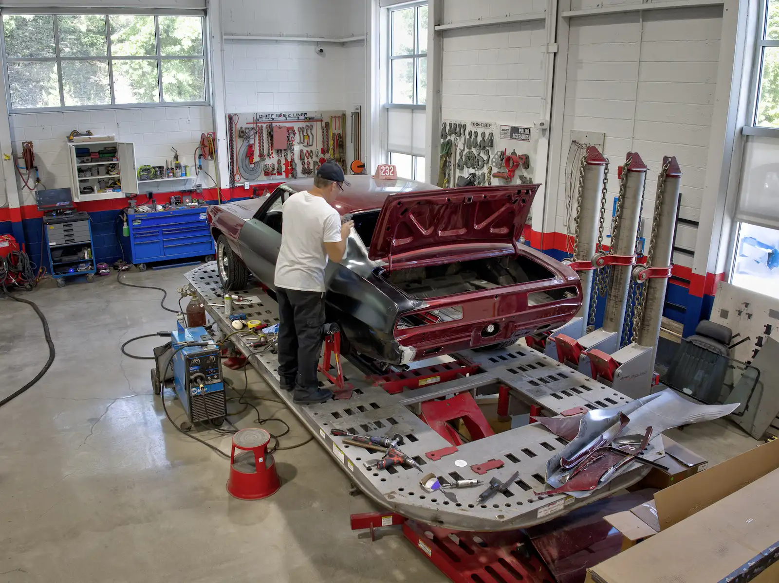 Auto body technician repairing a vehicle on a frame rack in the workshop
