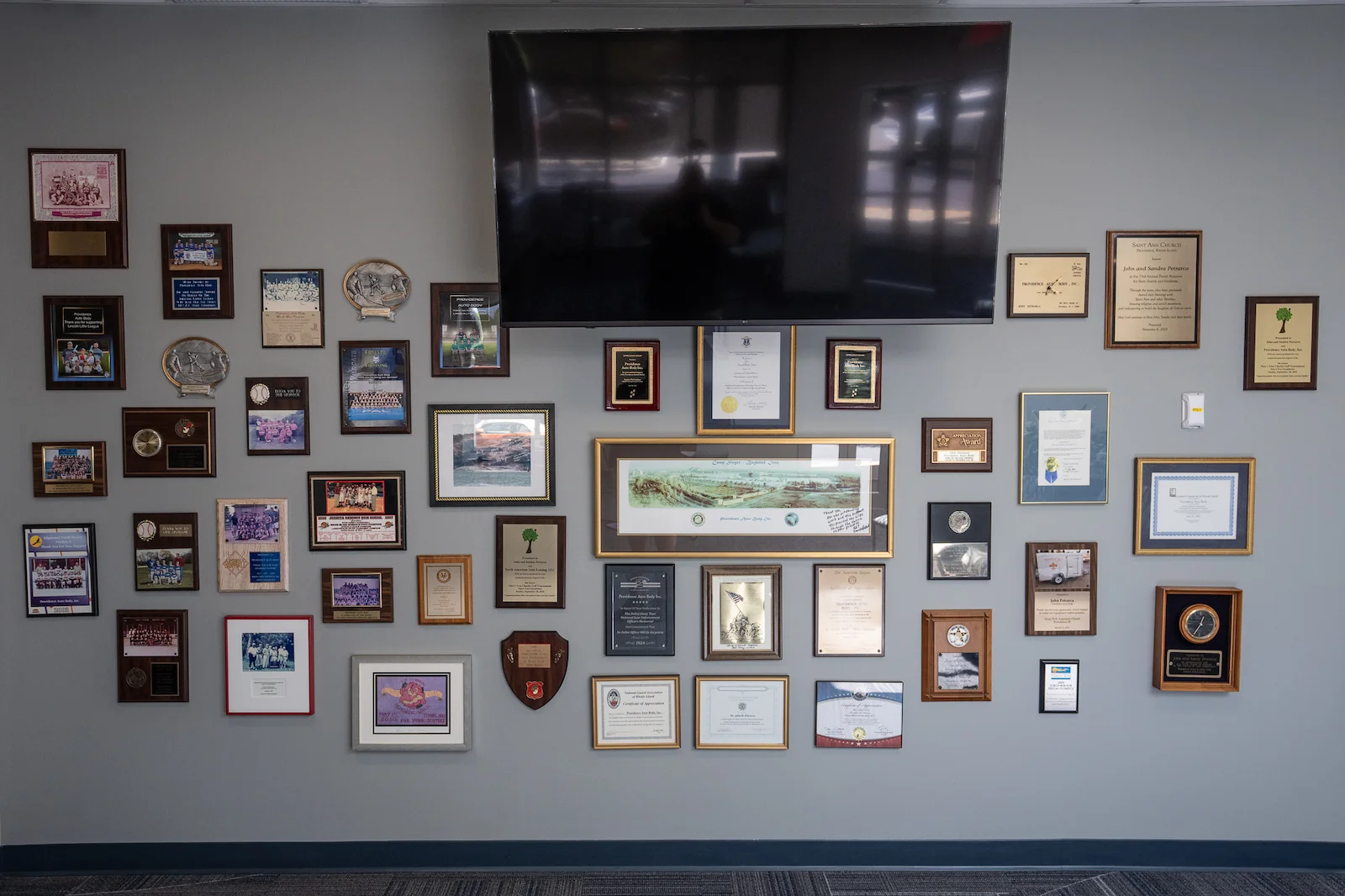 Providence Auto Body awards collage on a wall showing decades of service and certifications
